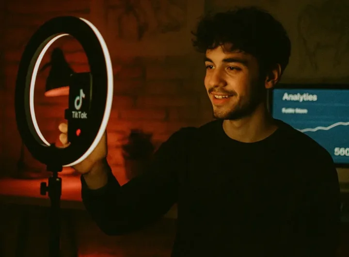 Creatore davanti a uno smartphone mentre registra un video impegnato con luci colorate
